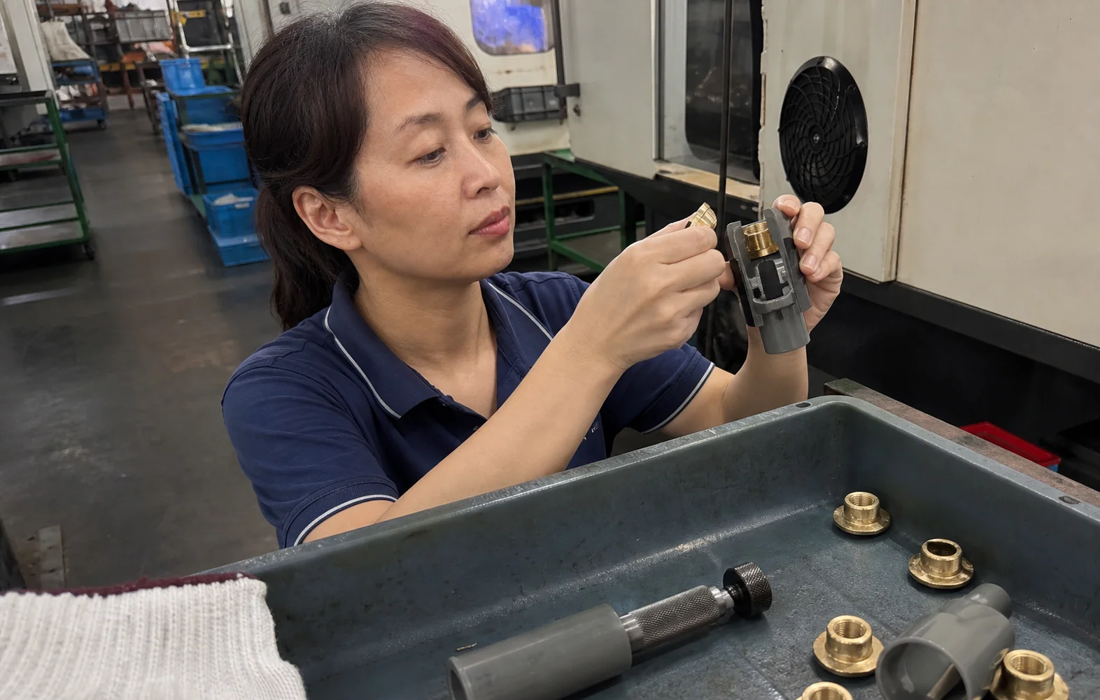 女性质量检验员在工作台核对法兰铜嵌件和塑胶试装柱